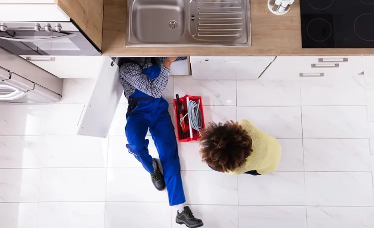 A person laying on the floor under a sink